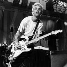 a young man playing an electric guitar on stage