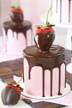 chocolate covered cake with strawberry on top and two other cakes in the back ground,