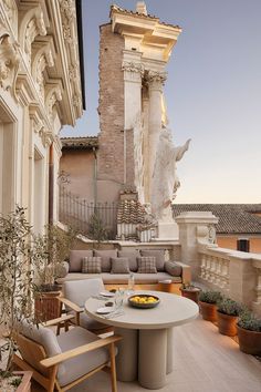 an outdoor patio with chairs, table and potted plants on the side of it