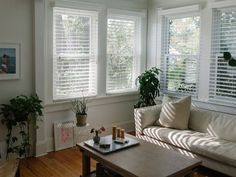 a living room filled with furniture and windows covered in white shuttered blinds on top of them