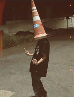 a man wearing a traffic cone hat standing in the middle of an empty parking lot