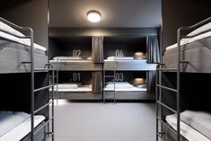 bunk beds are lined up in a room with black walls and white flooring,