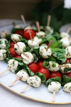 a white plate topped with tomatoes and mozzarella skewers