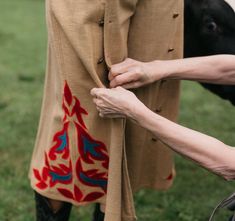 a woman is holding on to her pants with a cow in the background