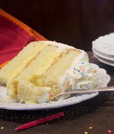 a slice of cake with white frosting and sprinkles on a plate