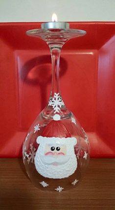 a wine glass with a santa clause on it and a red plate in the background