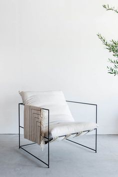 a white chair sitting next to a plant in a room with no one on it