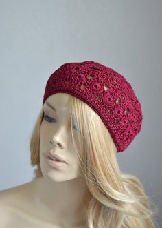 a mannequin head wearing a red hat with crocheted details on it