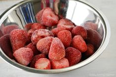 a metal bowl filled with strawberries covered in powdered sugar