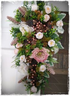 an arrangement of flowers and greenery in a vase on a door way or wall