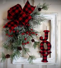 a red and black plaid christmas wreath hanging on a white door