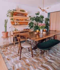 a dining room table surrounded by potted plants and other decorating items on shelves