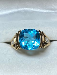 an oval blue topaz ring set in yellow gold with diamonds on the sides and side