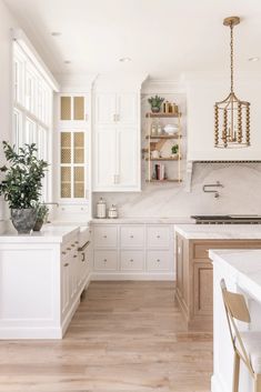 a large kitchen with white cabinets and wood flooring is seen in this image from the front view