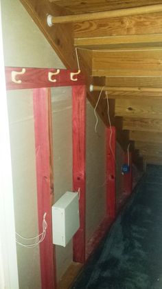 an unfinished room with red and white wires on the wall, and some electrical cords hanging from the ceiling