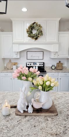 a kitchen counter with flowers in vases on top of it and candles next to it