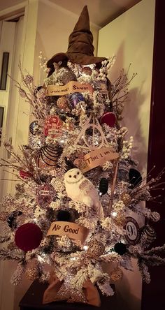 a white christmas tree decorated with harry potter themed ornaments and an owl ornament