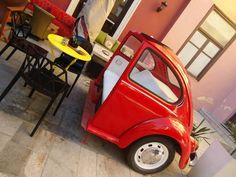 a small red car parked next to a table and chairs