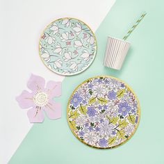 two plates with flower designs on them next to a drink cup and paper straws