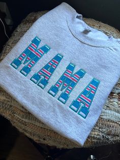 a white t - shirt with the word hawaii printed on it sitting on a wicker chair