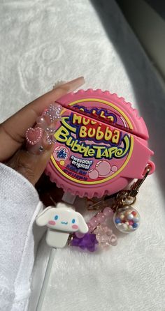 a hand holding a pink candy jar with charms on it and a keychain