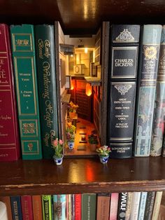 a book shelf filled with lots of books next to a vase and potted plant