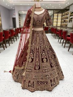 a bridal gown on display in a room full of red velvet chairs and tables