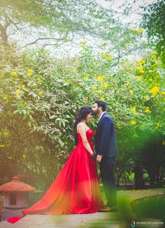 a man and woman standing next to each other in front of trees