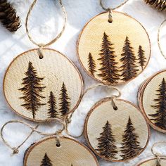 wooden ornaments with pine trees on them are hung from twine strings and decorated with twine