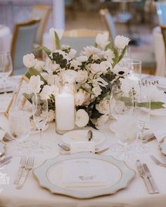 the table is set with white flowers and silverware