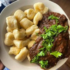 a white plate topped with meat and dumplings