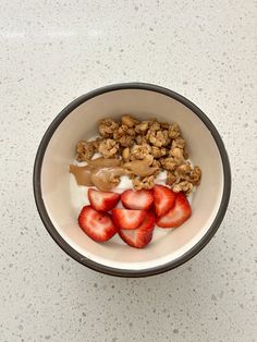 a bowl filled with yogurt and strawberries on top of a white counter