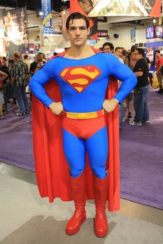 a man dressed as superman stands in front of a crowd at a convention or show