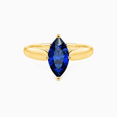 a yellow gold ring with a blue sapphire stone in the center, on a white background