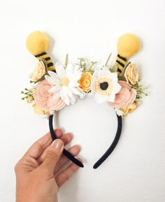 a hand holding a pair of scissors near a flower headband with bees on it