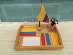 a wooden tray with various colored papers and a toy sailboat on top of it