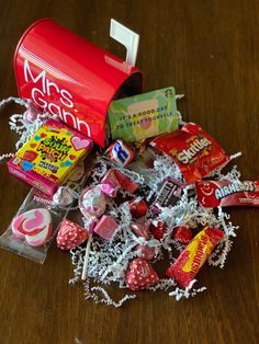 a pile of candy sitting on top of a wooden table next to a red can