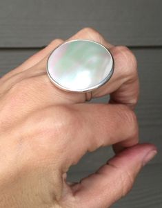 A large white round mother of pearl cabochon has been hand set in sterling silver. This ring is simple and elegant, the mother of pearl is the highlight of the ring. When the light hits this white mother of pearl cabochon hues of pink and grey emerge. There is also the natural texture of the mother pearl also adds depth and an organic quality to the stone. The cabochon is 30mm in size or 1 inch in size. Please specify which size you are purchasing when the order is placed. Remember that each mot White Mother Of Pearl Round Pearl Ring, Silver Mother Of Pearl Round Rings, White Mother Of Pearl Rings, Round Cabochon Mother Of Pearl Jewelry, Mother Of Pearl Rings For Anniversary, Gold Oval Engagement Ring, Rose Gold Oval Engagement Ring, Moissanite Engagement Ring White Gold, Twig Engagement Ring