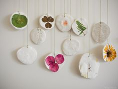 a group of ceramic flowers hanging from strings on a wall next to a white wall