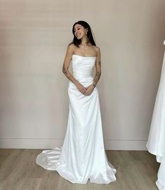 a woman in a white dress standing next to two dresses