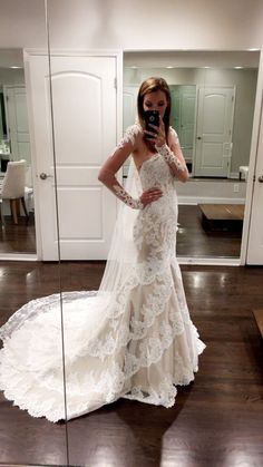 a woman in a wedding dress taking a selfie with her cell phone while standing in front of a mirror