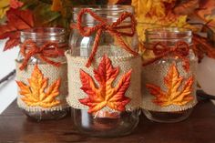 three mason jars with autumn leaves on them