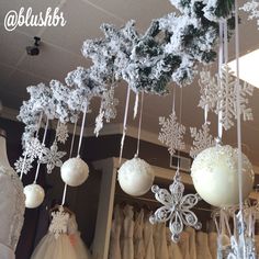 snowflakes and ornaments hanging from the ceiling in a bridal gown shop window