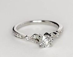 a white gold ring with three diamonds on the band and an oval shaped center stone