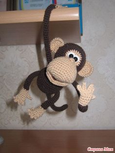 a crocheted monkey hanging from a shelf