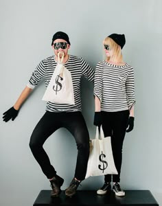 two people standing next to each other with bags in front of their faces and one holding a dollar sign