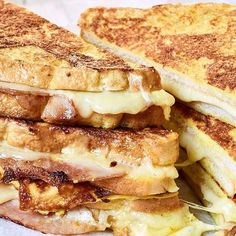 two grilled sandwiches stacked on top of each other with melted cheese and meats