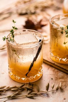 two glasses filled with drinks sitting on top of a wooden table