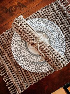 a table with two plates on it and a crocheted placemat in the middle