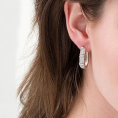 A contemporary classic, these diamond hoop earrings pair well with most any attire. Created in sterling silver, each sophisticated hoop features three rows of sparkling round diamonds. A pair of collars lined with channel-set baguette-cut diamonds adds interest to the style. Radiant with 1 ct. t.w. of diamonds and a brilliant buffed luster, these earrings secure with hinged backs. Modern Sterling Silver Hoop Diamond Earrings, Elegant Silver Hoop Earrings With Baguette Diamonds, Classic Hoop Earrings With Baguette Diamonds, Modern Channel Set Cubic Zirconia Earrings, Classic Silver Baguette-cut Hoop Earrings, Classic Silver Hoop Earrings With Baguette Diamonds, Classic Silver Baguette Cut Hoop Earrings, Modern Sterling Silver Hoop Earrings With Brilliant Cut, Silver Baguette Cut Hoop Earrings